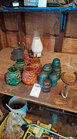 Overview of vintage glass insulators, oil lamp chimney, bell, candle and horseshoe on wooden surface