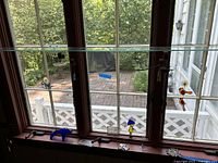 Photo of multiple glass sun catchers hanging and displayed on a window. Included are dolphin, birds, flowers, and mushrooms shapes. Pieces vary in color like blue, orange, and purple.