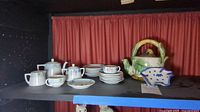 Full set displayed on shelf with teapot, creamer, sugar bowl, teacups, saucers, and tea bag holder