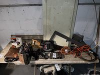 Drop light, 7 inch blade saw, electric tracker device, tool belt and additional tools on table against wall