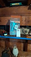 Photo shows one Bushnell Vital V2 12MP trail camera in original packaging on shelf with other items.