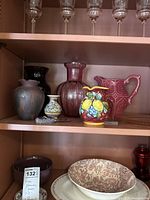 Various vases including glass and ceramic, a ceramic pitcher, a small decorated vase, and a small trinket dish displayed on a shelf.