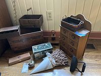 Overall photo of vintage wooden boxes and other decor items including Winchester ammunition box, small wooden cabinet, metal basket, dried flower cone, and metal items with handles.