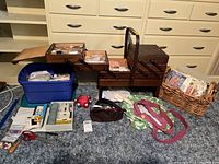 Wide view of the sewing box setup on carpet with various sewing supplies including patterns, scissors, and a basket of sewing items.