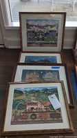 Four framed Charles Wysocki prints stacked on floor near window, showing detailed Americana scenes and varied wooden frames.