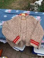 Front view of heavy marled beige/brown zip sweater with red accents
