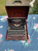 Typewriter inside open carry case showing keys, ribbon spools, handle visible