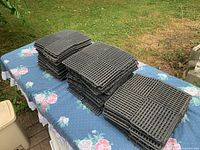 Stacks of black interlocking slatted tiles on table