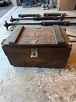Front view of antique wooden chest showing metal latch and wood wear.