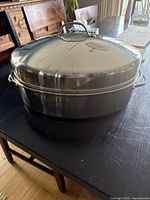 Closed roasting pan with lid and handle, showing the exterior oval shape and stainless steel finish.