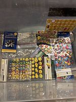 Assorted kids stickers including emoji and cartoon character designs, and rhinestones in original packaging on a flat surface.