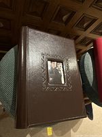 Brown wedding photo album with embossed frame and photo window showing a wedding couple