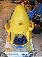 Yellow Sea-Doo Sea Scooter with blue propeller guard seen from top angled views showing dual handles and brand logos.