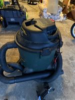 Green Shop Vac Ultra wet/dry vacuum with black hose and top handle, showing the overall unit with hose coiled around base