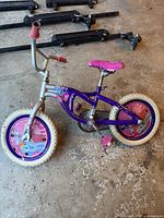 Full side view of the purple My Little Pony child's bike showing front and rear wheels, frame, seat, pedals, and handlebar grips