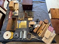 Lot overview showing beeswax blocks, vintage wooden case, assorted files, chisels, clamps, buffing wheels and brushes spread on table