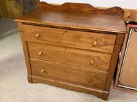 Full front view of a vintage wooden dresser with three drawers and decorative wood inlays. Shows overall condition and shape.