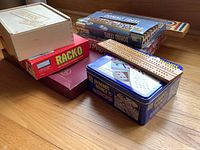 Photo showing several boxed games stacked including Racko, Dominoes, Cribbage board, THINGS wooden box