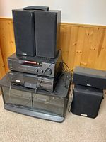 Full view of the stereo components stacked on cabinet with speakers placed on and around cabinet.