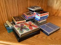 A variety of playing cards and poker card boxes, stacked on a wooden shelf corner.
