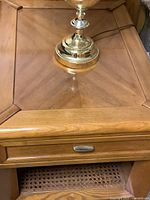 Close-up showing wooden side table top with drawer and brass lamp base