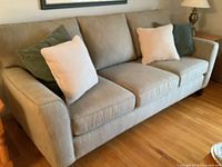 Angled view of sofa showing fabric texture, seat and back cushions, and toss pillows.