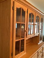 Close-up of the side profile showing the oak wood frame and glass-paned door with wooden knob.