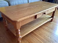 Front-side angle showing tabletop, turned legs, single drawer and lower shelf