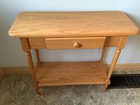 Front view of oak hallway table showing drawer and lower shelf.