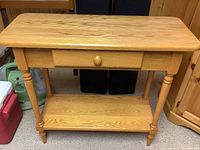 Front view of golden oak console table showing rectangular top, turned legs, single drawer and lower shelf