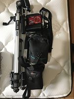 Full view of Slik 35D tripod, Nikon Coolpix camera, and black camera bags arranged on a mattress.