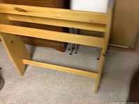 Image of a natural pine wood blanket holder frame with horizontal slats captured indoors on a carpeted floor.