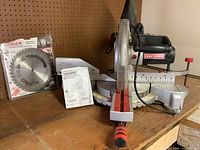 Craftsman sliding compound mitre saw with angle scale and motor in view on wooden surface.