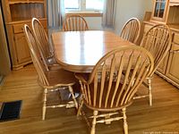 Full view of oak dining table with eight Windsor chairs arranged around it in a dining room