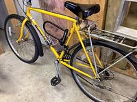 Full side view of the yellow Bianci road bike, showing the frame, saddle, crank, pedals and locking mechanism.