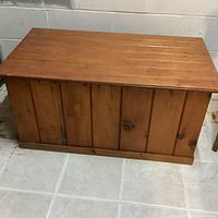 Front view of vintage wooden blanket box showing vertical paneling and natural wood grain finish.