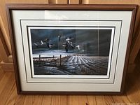 Framed print titled 'Winter Snows' showing a winter landscape under a dark sky with ducks flying, visible wooden fence posts and snow covered furrows in the field.