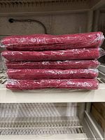 Stack of 10 red towels still in plastic wrapping, showing thickness and color