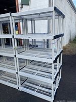 Two sets of gray plastic 5-tier shelving units outdoors with visible black trim and ventilation slats on shelves.