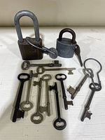 Photo of two vintage Yale padlocks with keys and 11 skeleton keys laid out on a white surface.