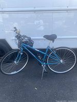 Side angle of blue Bianchi cross-terrain bike showing frame, handlebars with basket, pedals, and tires.