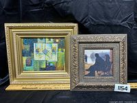 Two framed paintings side by side on black fabric background, ruler present for scale