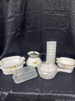 Full set of CorningWare Wildflower items arranged on black cloth, showing casseroles, coffee pot, covered pot, bowls and glass butter dish