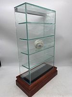 Front angle view showing entire glass cabinet and wooden base with baseball inside for scale.