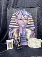 Full grouping showing large King Tutankhamun puzzle, small bust sculpture, and stone relief on black background