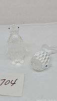 Two clear crystal figurines, a standing penguin with black eyes and a whale with blue eyes, both detailed cut surfaces.