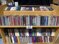 Shelf of music CDs showing three rows filled with assorted CDs in jewel cases, various artists and genres.