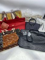 Wide view of various new handbags and tote bags in different colors and materials, including red, black, translucent brown with pattern, and clear bags.