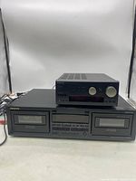 Front view of ONKYO stereo cassette tape deck TA-RW244 with dual cassette compartments and receiver amplifier on top showcasing controls and display.