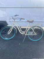Full side view of the cream-colored Schwinn Fairhaven cruiser bike with turquoise rims and brown saddle.